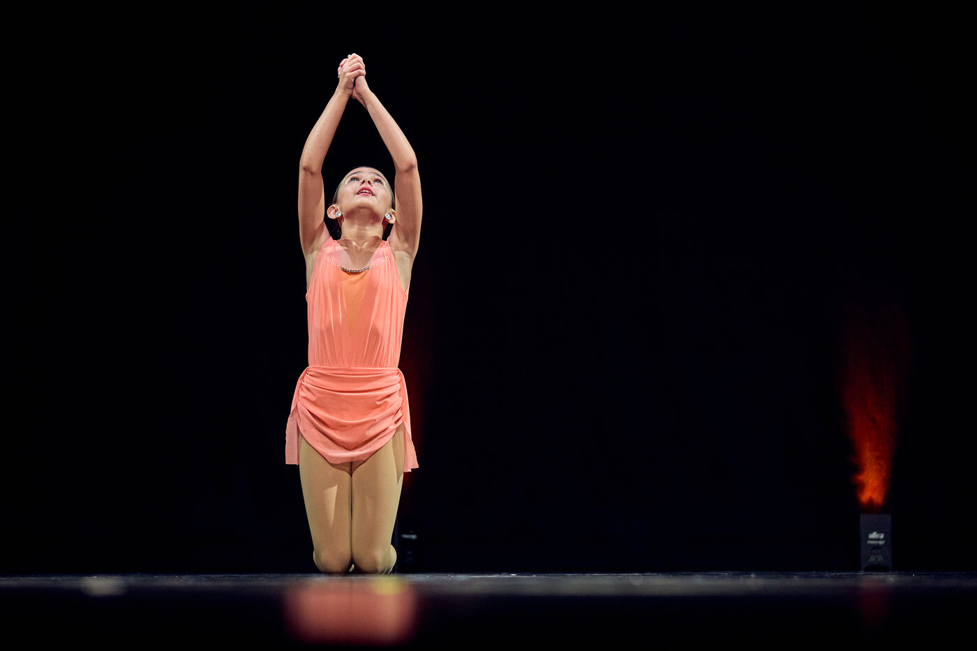 Young dancer in a peach costume reaching her arms overhead