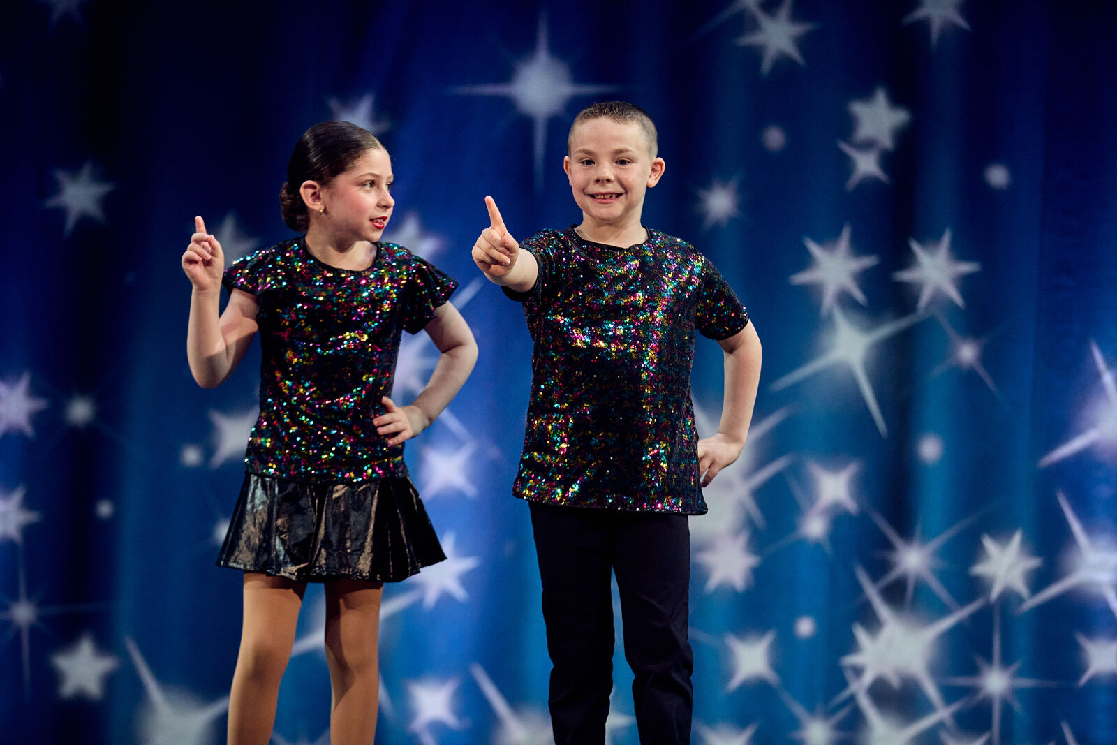 Two young dancers striking a pose in sequined costumes