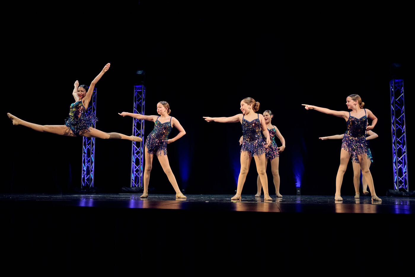 AFDS dancers spread across the stage in teal costumes