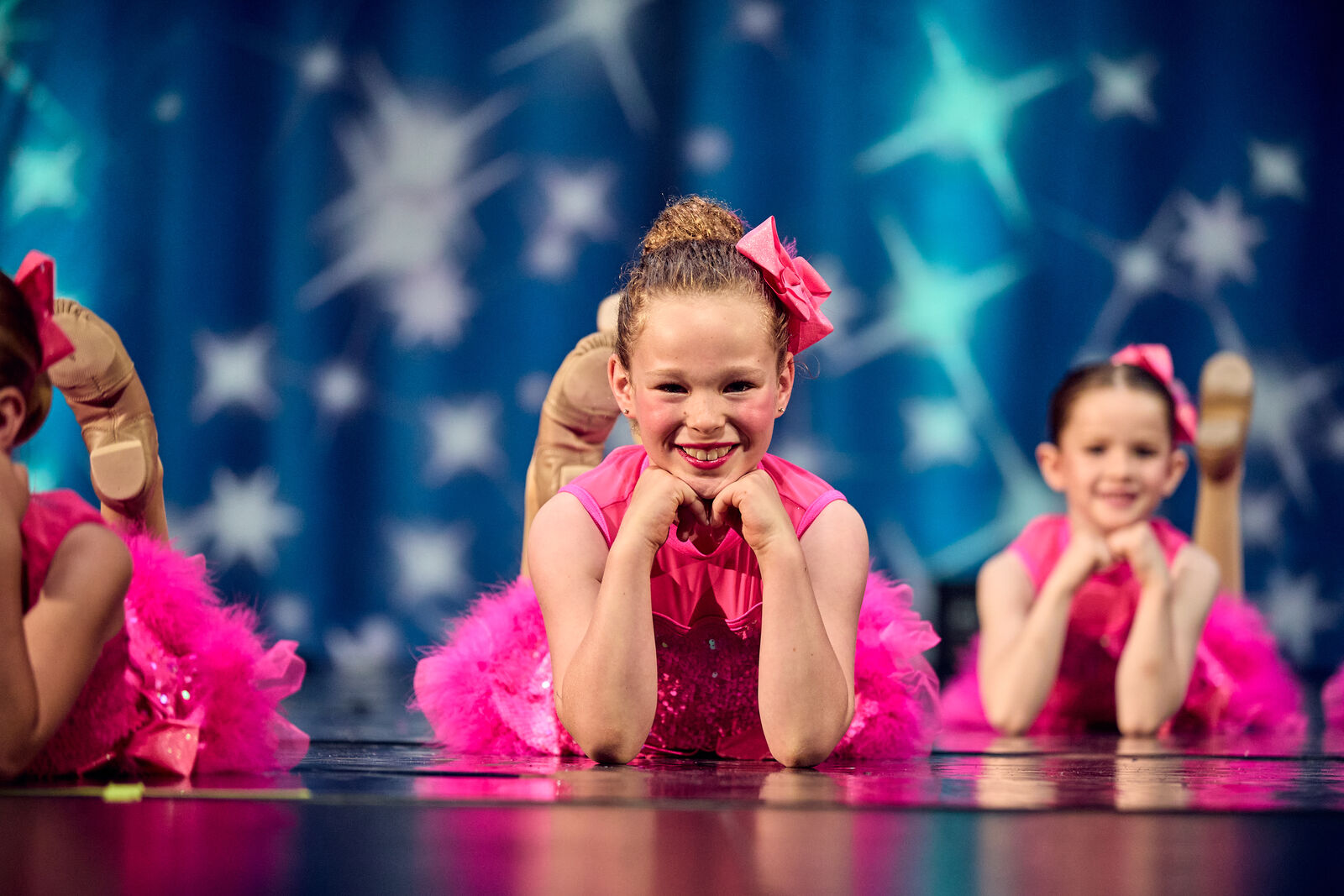 Two young dancers in pink tutus smiling on stage